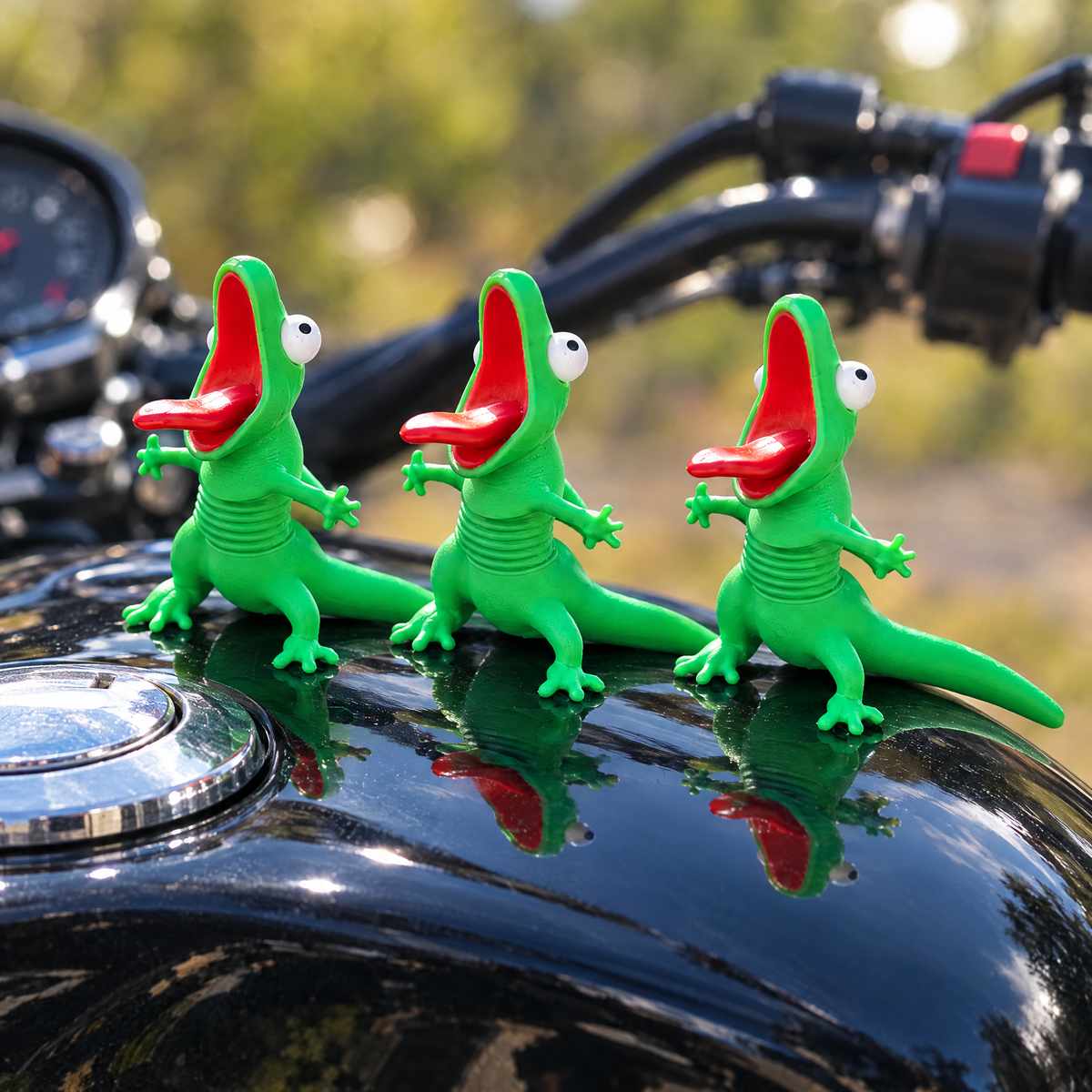 Three lizard buddies lined up on a motorcycle fuel tank